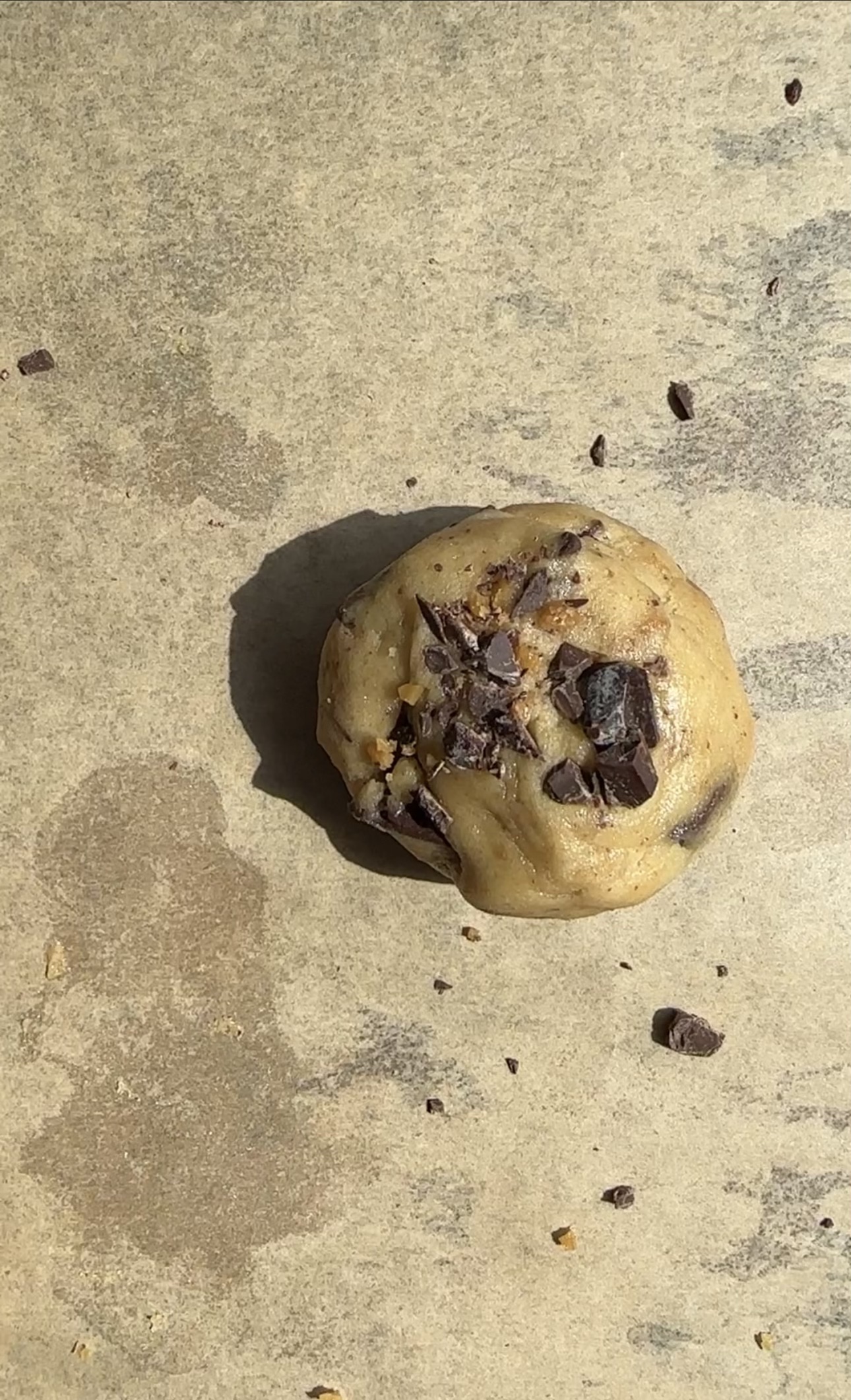 cookie dough ball about to go in oven with extra chips
