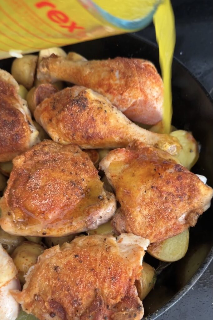 Pouring garlic lemon sauce over chicken and potatoes