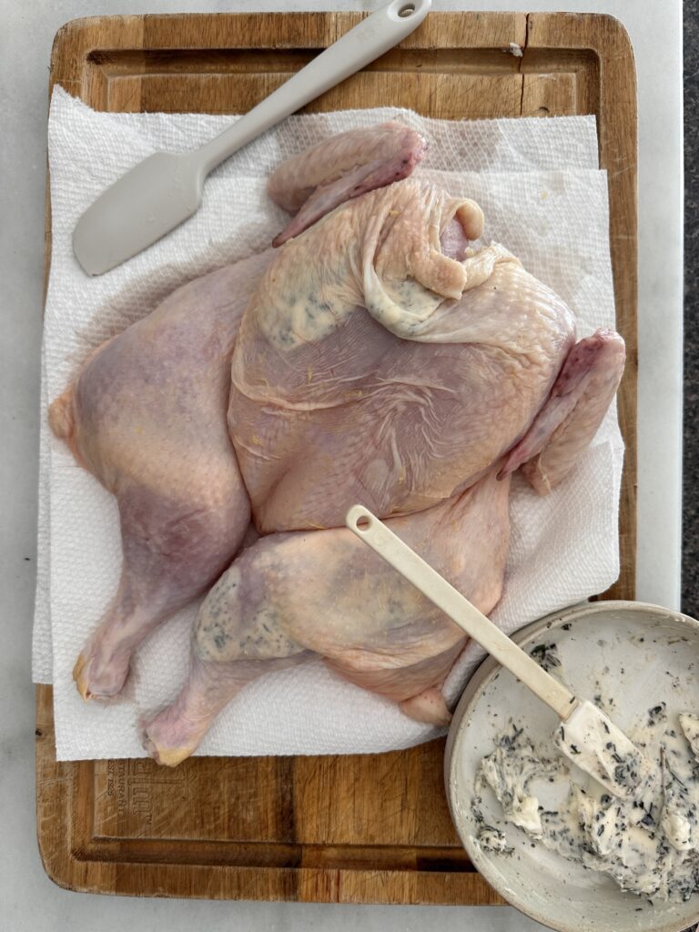 adding herb butter to chicken