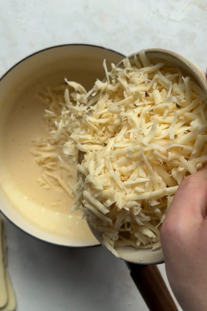 adding shredded cheese to queso mixture