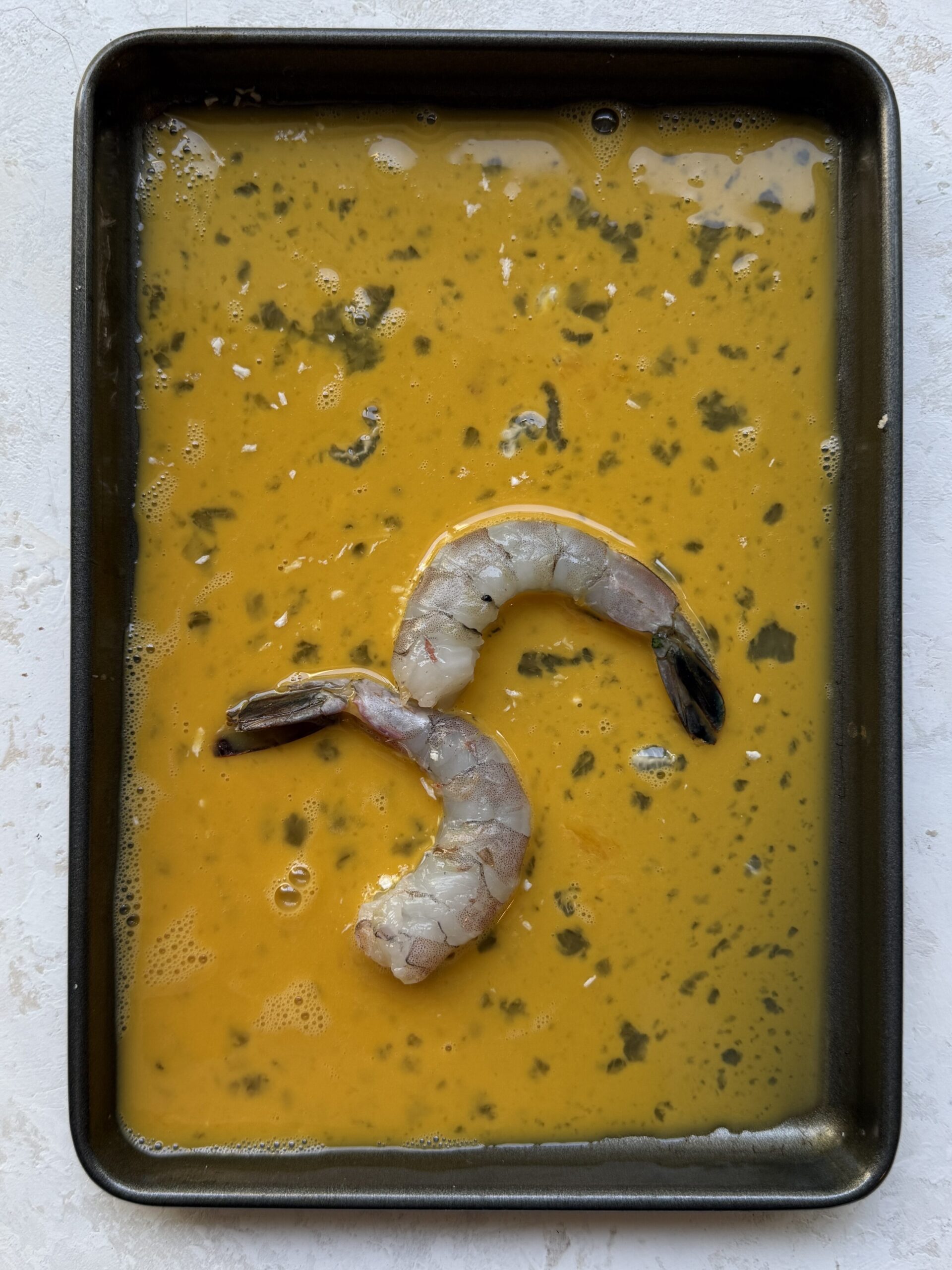 Raw shrimp dipped in seasoned egg before making coconut shrimp.